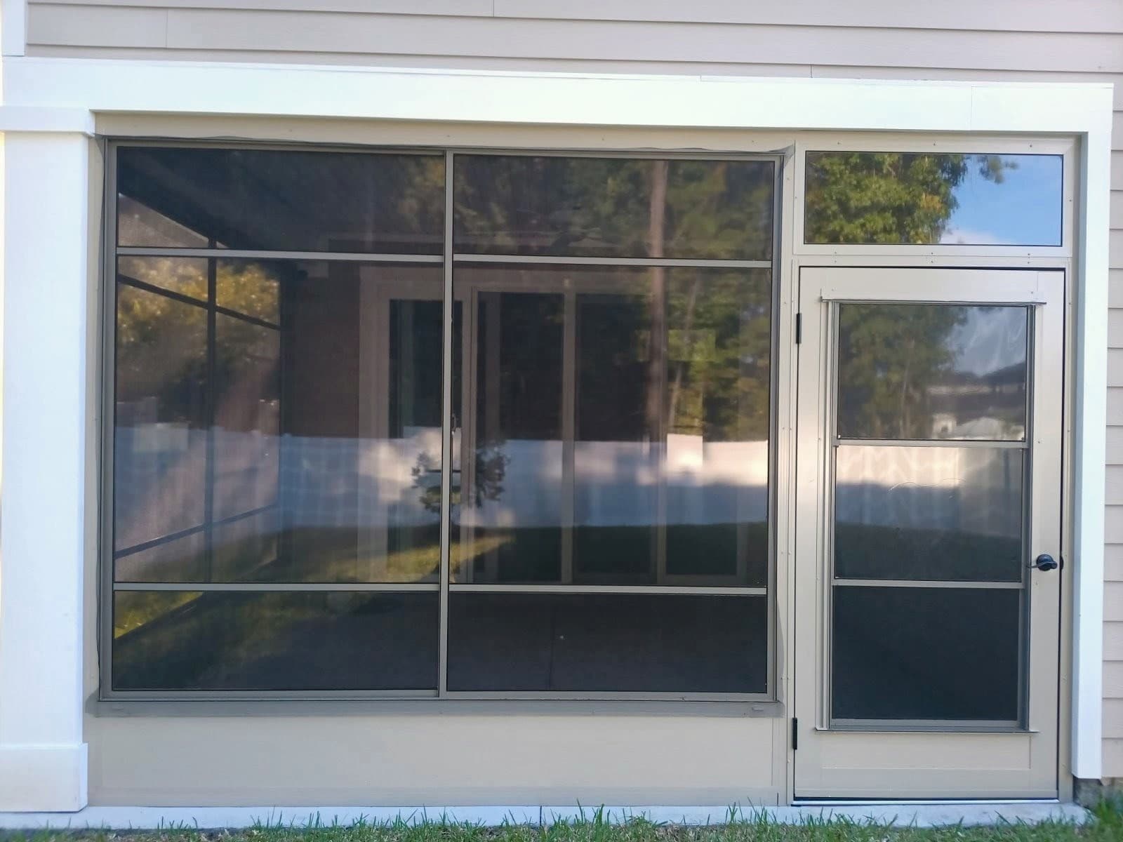 Sandstone-framed porch enclosure with large vinyl windows and a screen door